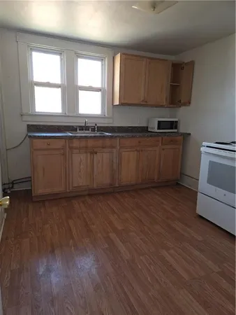a kitchen with granite countertop wooden floors a stove a sink and a window