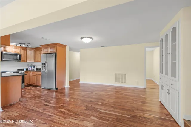 a view of kitchen with refrigerator stove and wooden cabinets