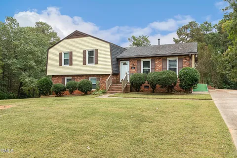 a front view of a house with a yard and potted plants