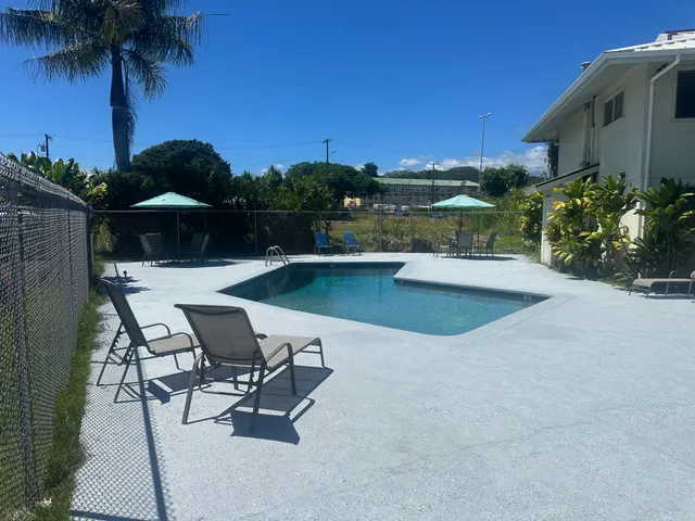 a view of a swimming pool with a table and chairs under an umbrella