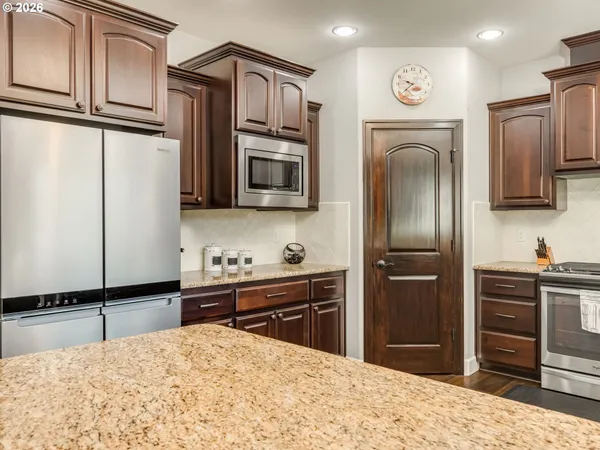 a kitchen with stainless steel appliances granite countertop a refrigerator a stove a sink and a microwave