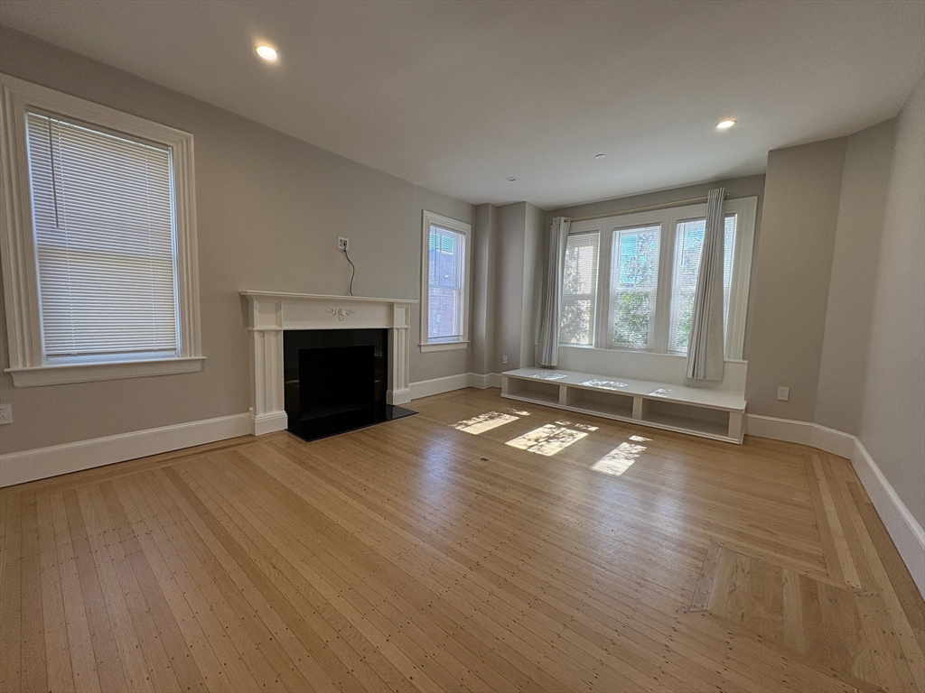 15 Lanark Road, Unit G Brookline, MA 02445 - Photo 25 of 30 an empty room with wooden floor fireplace and windows