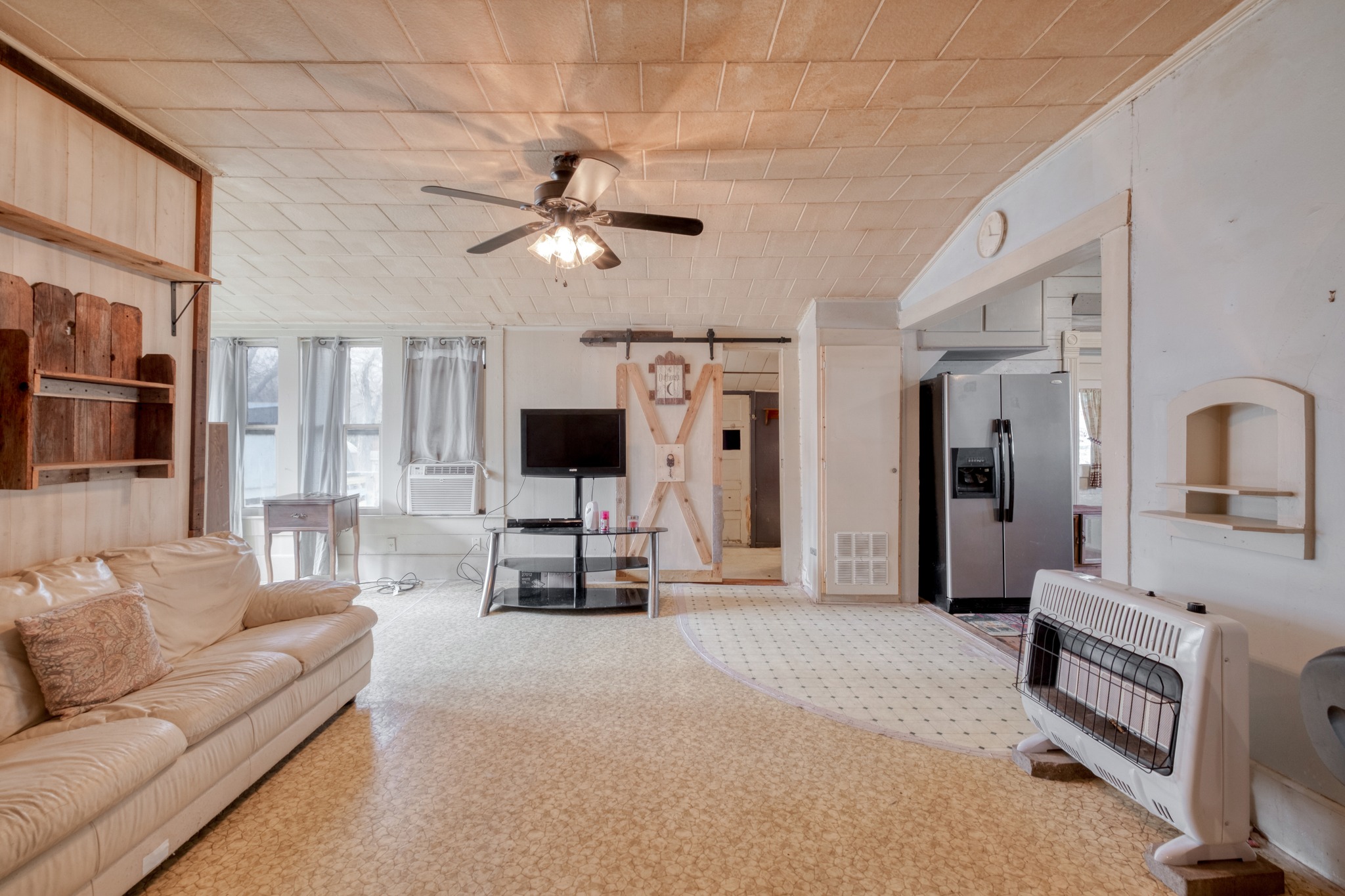 300 South Rio Grande Street Granger, TX 76530 - Photo 8 of 25 Living area with a barn door, heating unit, ceiling fan, cooling unit, and vaulted ceiling