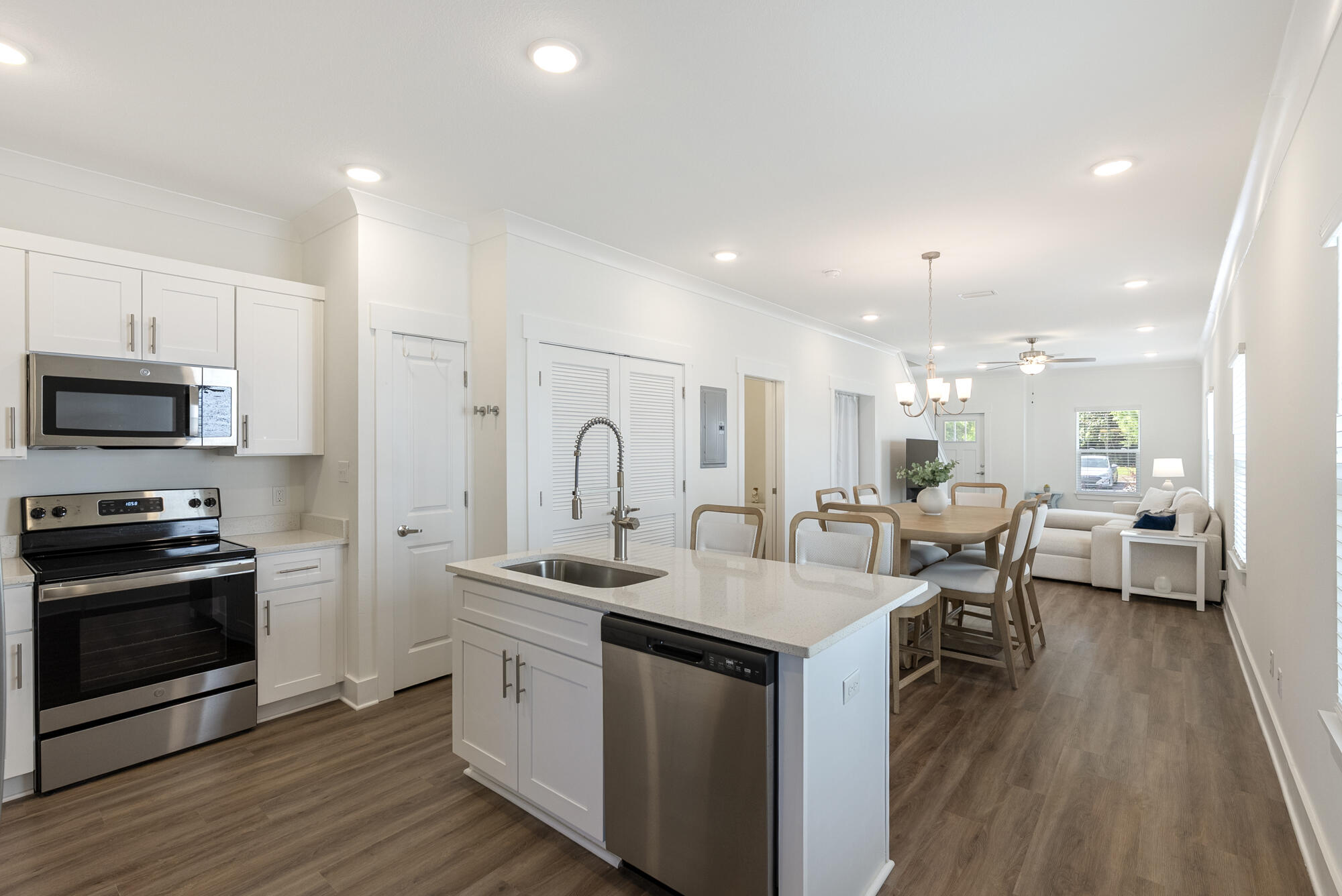 a open kitchen with stainless steel appliances kitchen island granite countertop a stove a sink a refrigerator and white cabinets with wooden floor