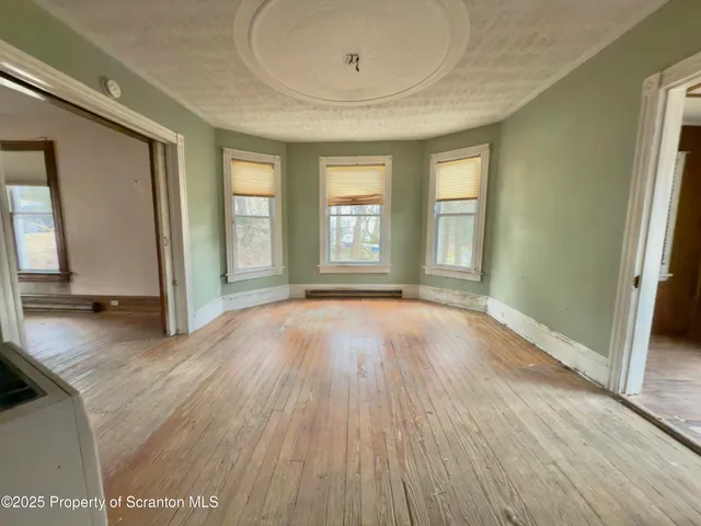 a view of an empty room with window and wooden floor