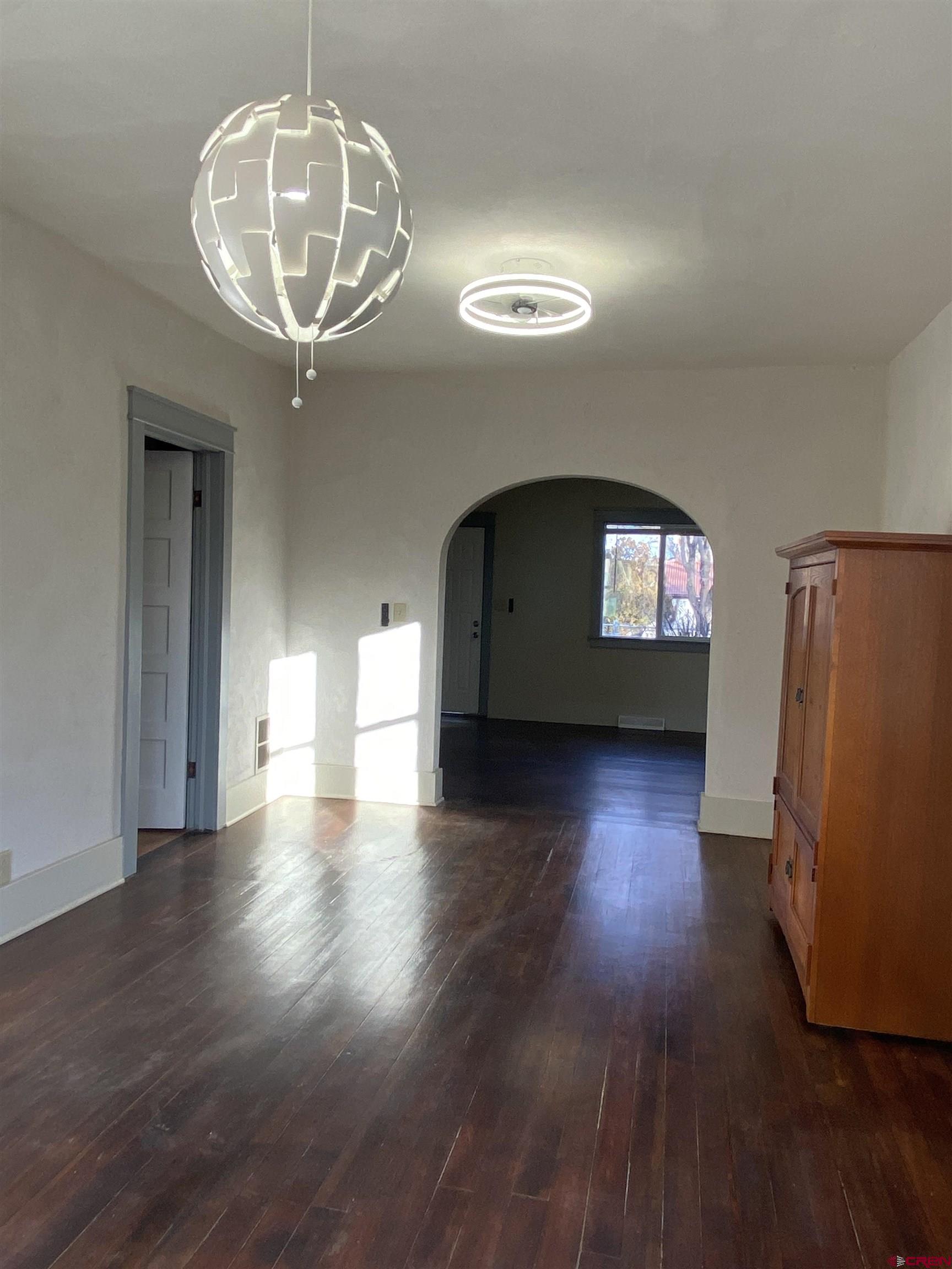121 South Washington Street Cortez, CO 81321 - Photo 3 of 33 a view of empty room with wooden floor and chandelier