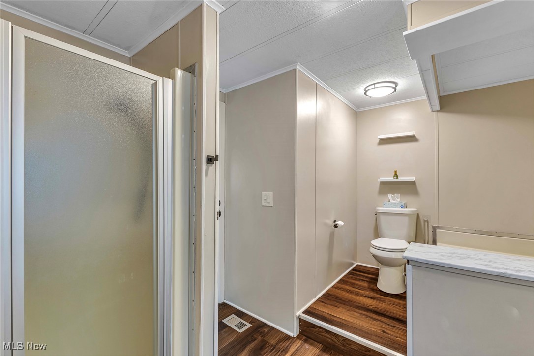 35157 Center Ridge Road, Unit 120 North Ridgeville, OH 44039 - Photo 20 of 25 Full bathroom featuring dark wood-type flooring, crown molding, and a stall shower