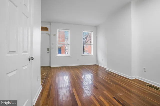 an empty room with wooden floor and windows