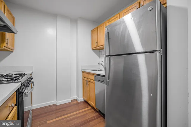 an empty room with wooden floor and a kitchen