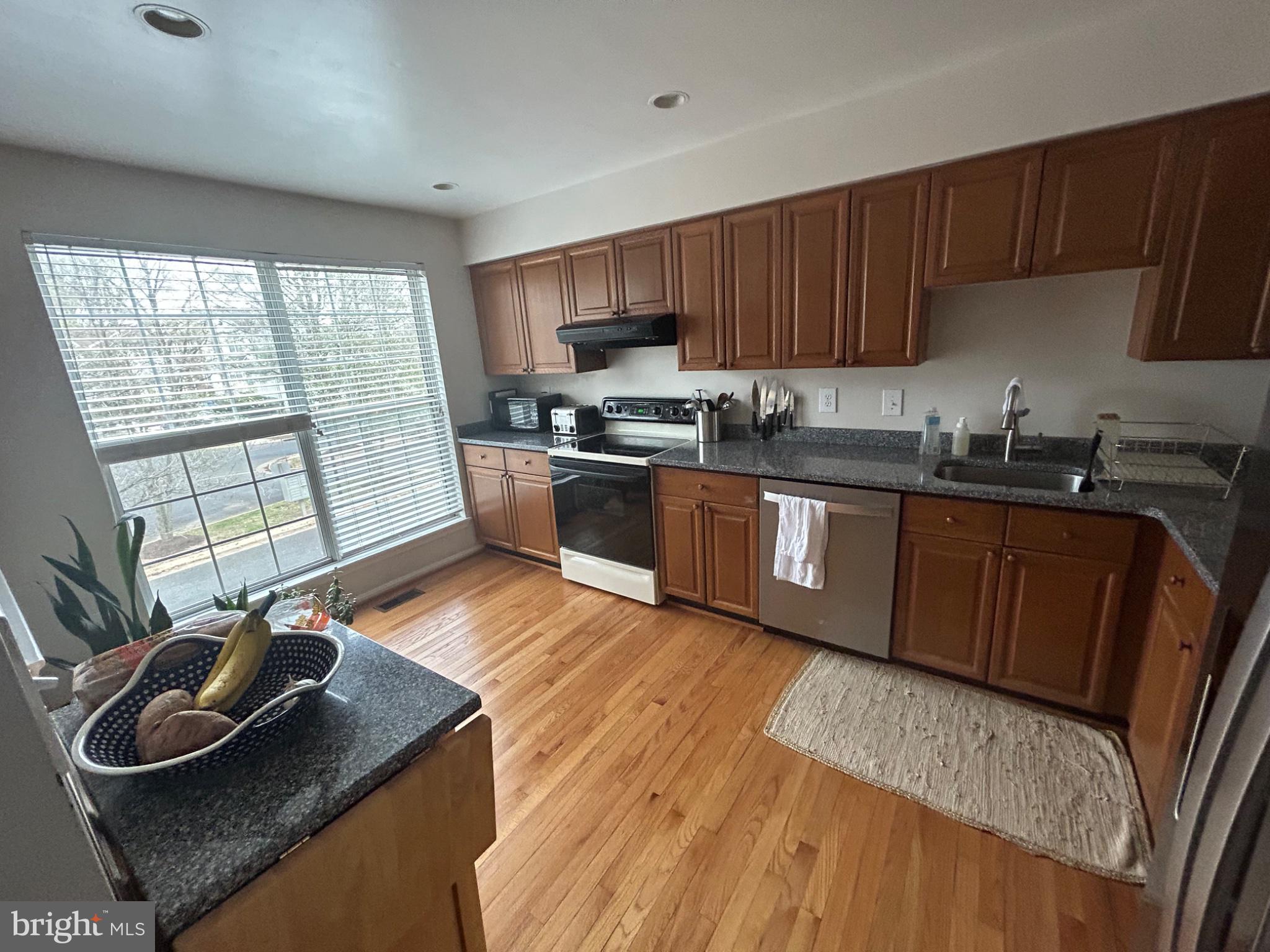5833 Pin Oak Commons Court Burke, VA 22015 - Photo 3 of 15 a kitchen with granite countertop wooden cabinets a sink and a stove