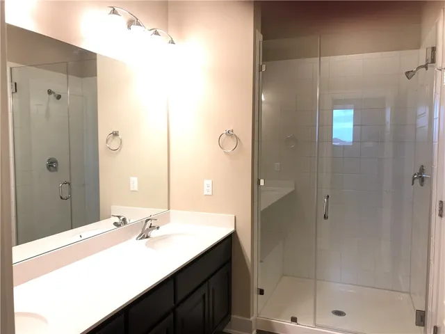 a bathroom with a shower sink vanity and mirror