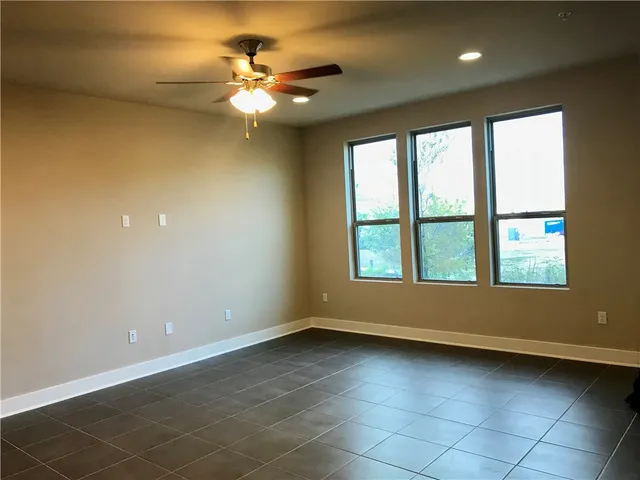 en empty room with windows and chandelier fan