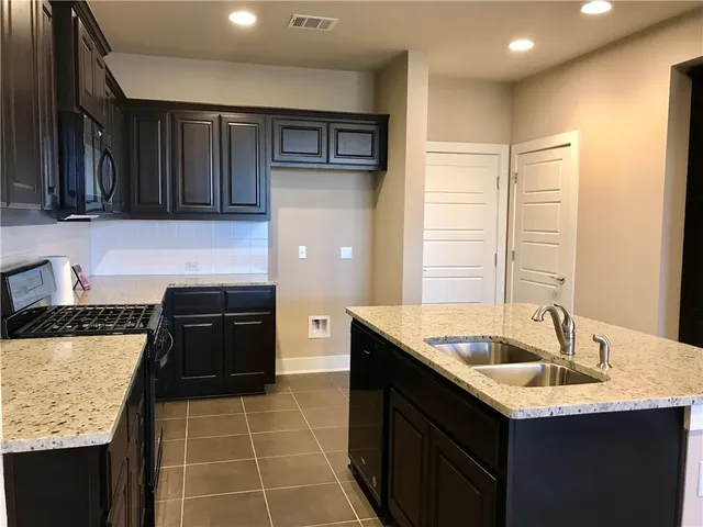 a kitchen with a sink a stove and cabinets