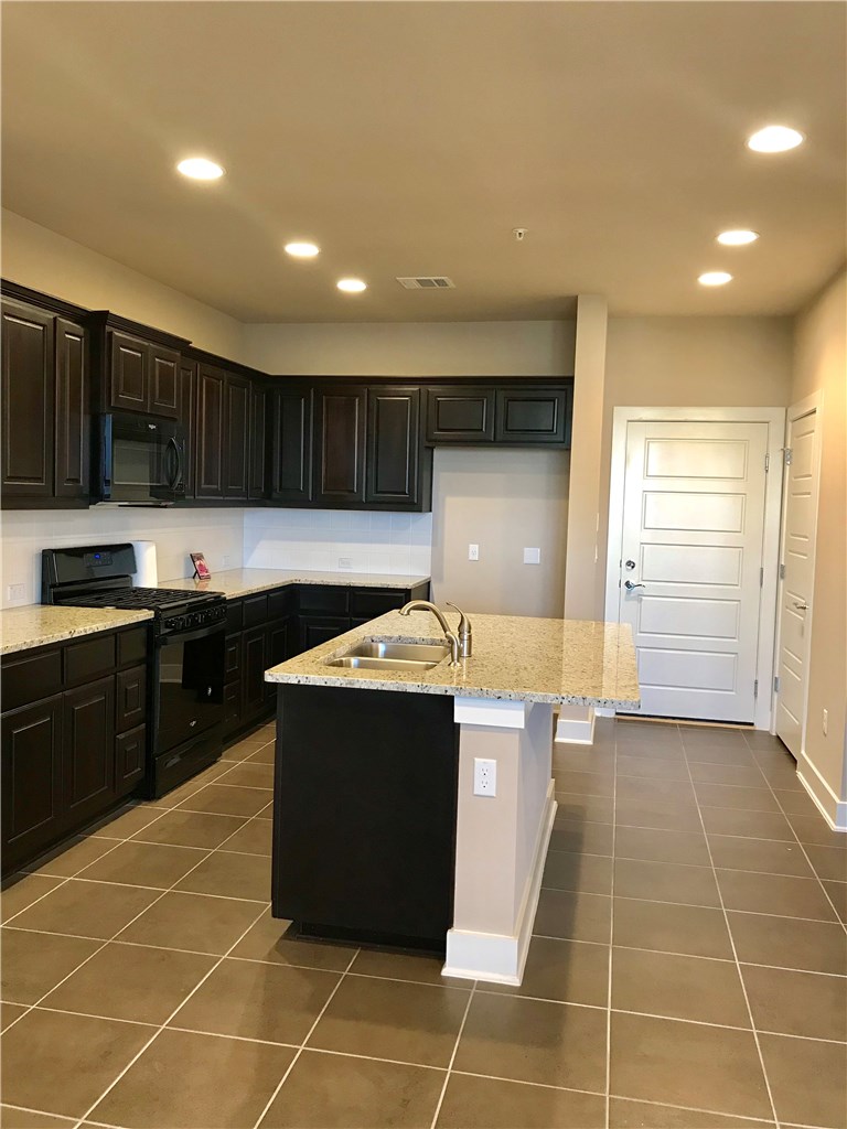 6814 East Riverside Drive, Unit 95 Austin, TX 78741 - Photo 8 of 23 a kitchen with granite countertop a stove a sink and a refrigerator