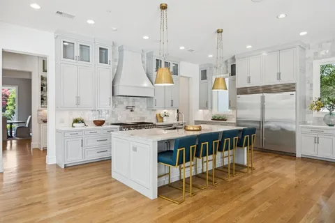 a large kitchen with stainless steel appliances kitchen island granite countertop a stove a sink a refrigerator and a dining table with wooden floor