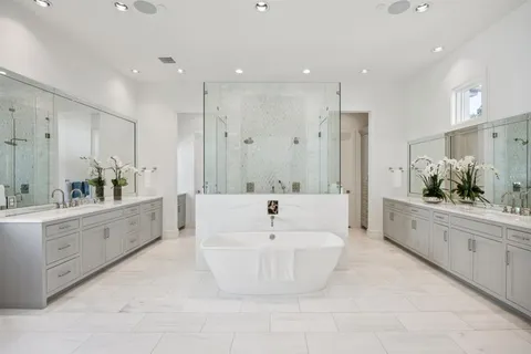 a large white bathroom with a large tub sink vanity and mirror