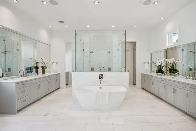 a large white bathroom with a large tub sink vanity and mirror
