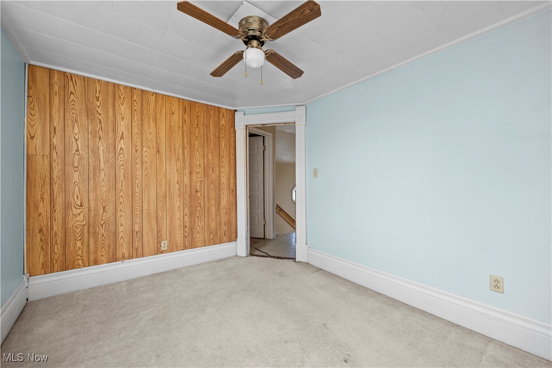 6927 North Wildacre Road Curtice, OH 43412 - Photo 27 of 44 Spare room featuring wooden walls, carpet, ceiling fan, and a baseboard radiator