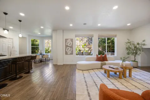 a living room with furniture kitchen view and a wooden floor