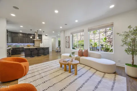 a kitchen with stainless steel appliances granite countertop a stove a refrigerator a sink dishwasher with a dining table and chairs with wooden floor