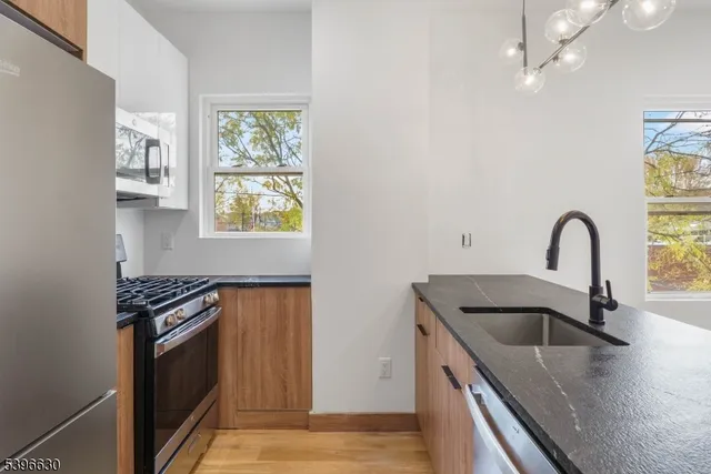 a kitchen with granite countertop a stove a sink and a refrigerator