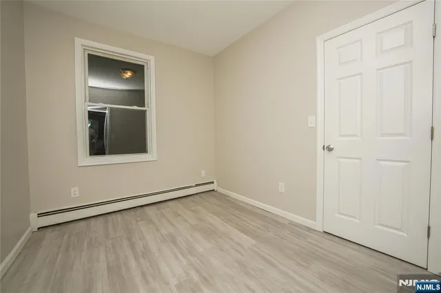 a view of an empty room with closet and a window