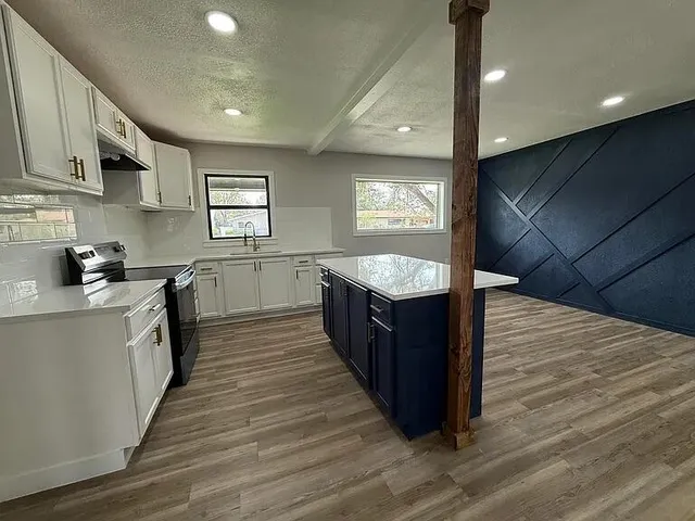 a large kitchen with stainless steel appliances granite countertop a large counter top a stove a sink and a refrigerator