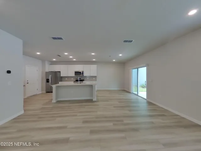 a view of kitchen with kitchen island a sink wooden floor and a refrigerator
