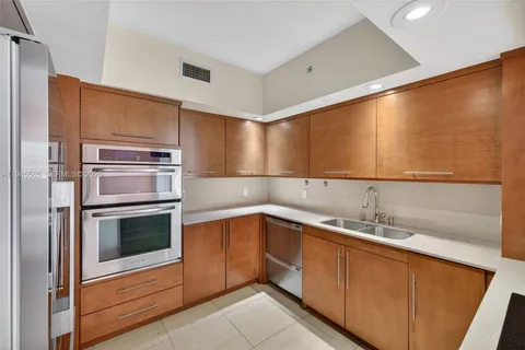 a kitchen with a sink and a dishwasher with wooden floor