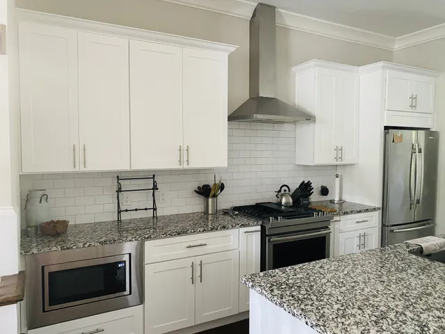 a kitchen with kitchen island granite countertop a sink stainless steel appliances and white cabinets