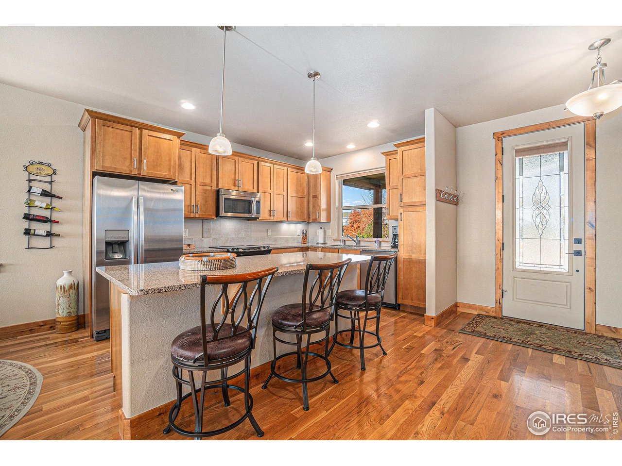 1827 Fromme Prairie Way Fort Collins, CO 80526 - Photo 6 of 21 a kitchen with stainless steel appliances kitchen island granite countertop a dining table chairs and granite counter tops