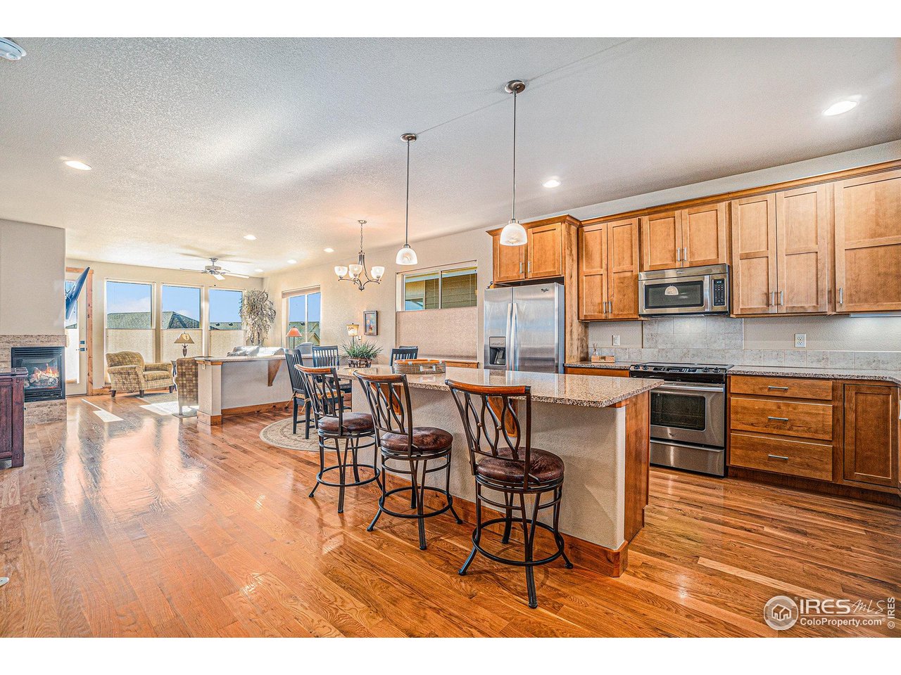 1827 Fromme Prairie Way Fort Collins, CO 80526 - Photo 7 of 21 a open kitchen with stainless steel appliances granite countertop a stove top oven a sink a dining table and chairs with wooden floor