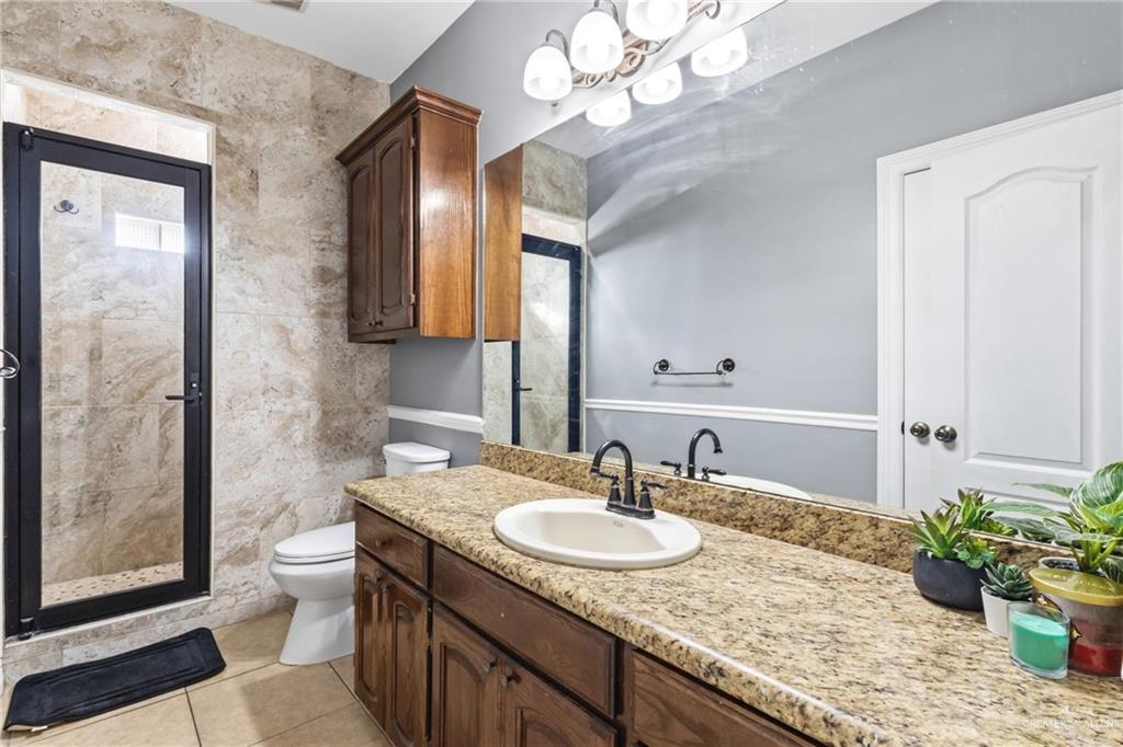 22602 Rio Rancho Road Harlingen, TX 78552 - Photo 12 of 26 a bathroom with a granite countertop sink a toilet and a mirror
