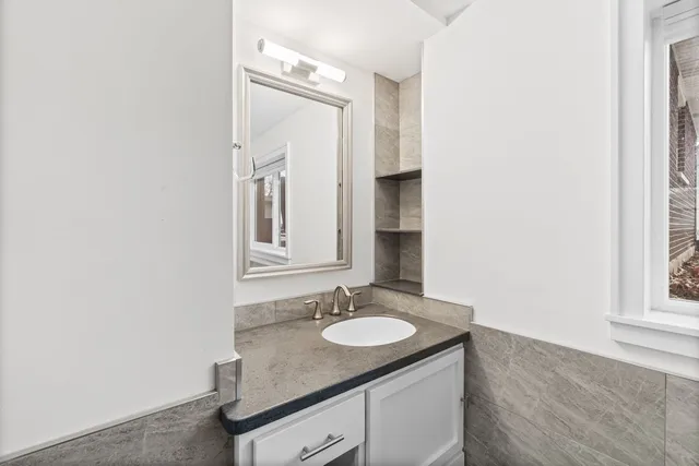 a bathroom with a granite countertop sink and a mirror