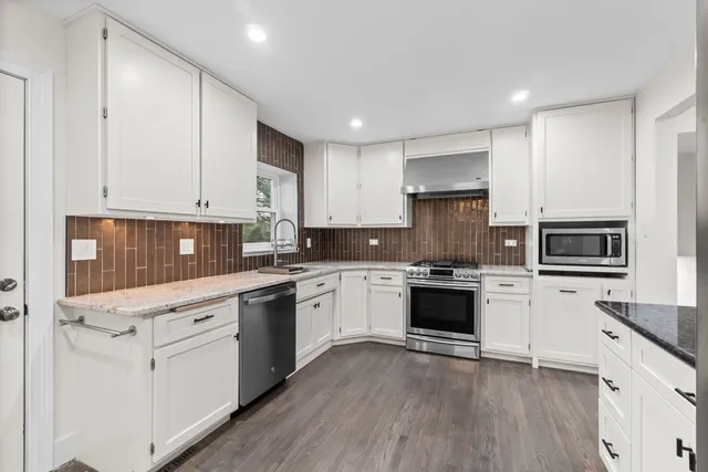 a kitchen with stainless steel appliances granite countertop refrigerator a stove top oven a sink dishwasher and white cabinets with wooden floor