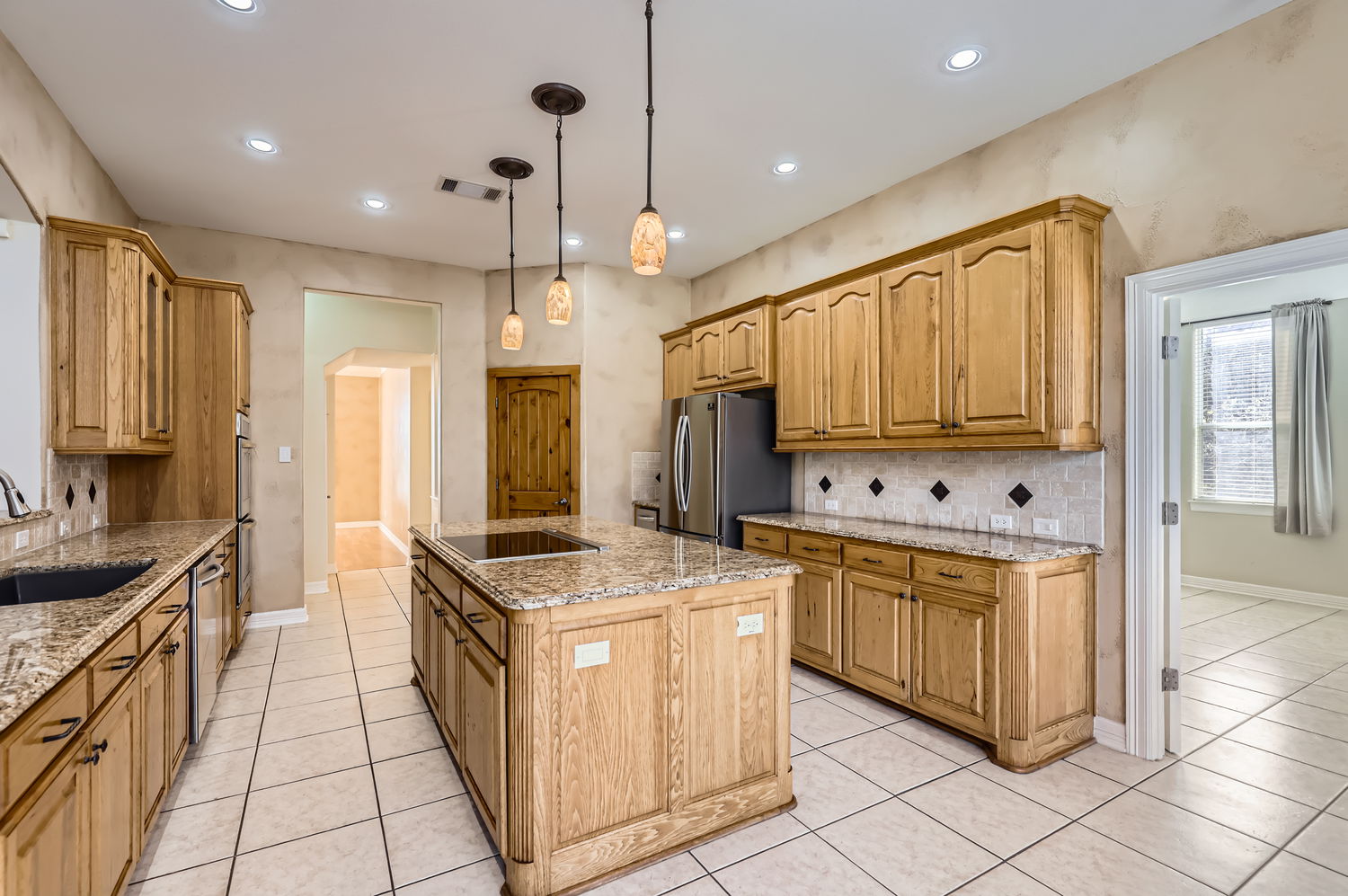 210 Amandas Way Leander, TX 78641 - Photo 14 of 38 Kitchen with light tile patterned floors, stainless steel appliances, backsplash, a kitchen island with sink, and a sink