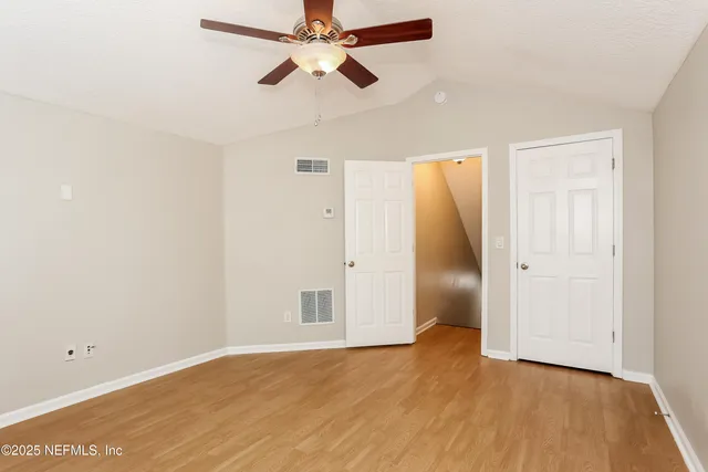 an empty room with wooden floor and fan