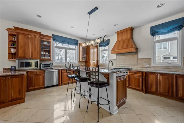 a kitchen with stainless steel appliances granite countertop wooden cabinets a stove a sink a dining table and chairs