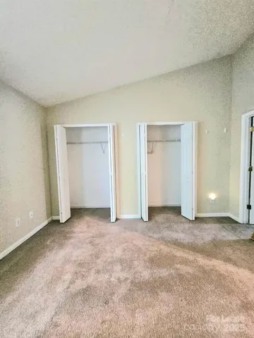 a view of an empty room with closet and entryway