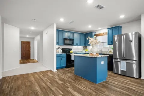 a kitchen with stainless steel appliances granite countertop a refrigerator a stove top oven and a refrigerator with wooden floor