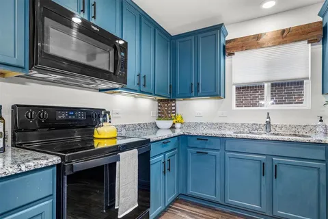 a kitchen with granite countertop a sink stainless steel appliances and cabinets