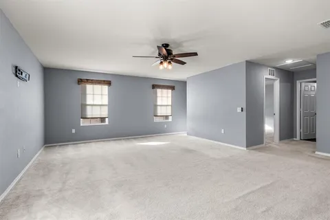 an empty room with windows and ceiling fan