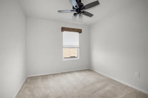 an empty room with a window and a fan