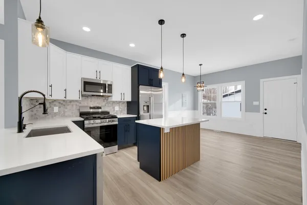 a kitchen with stainless steel appliances kitchen island a sink a stove a refrigerator and cabinets