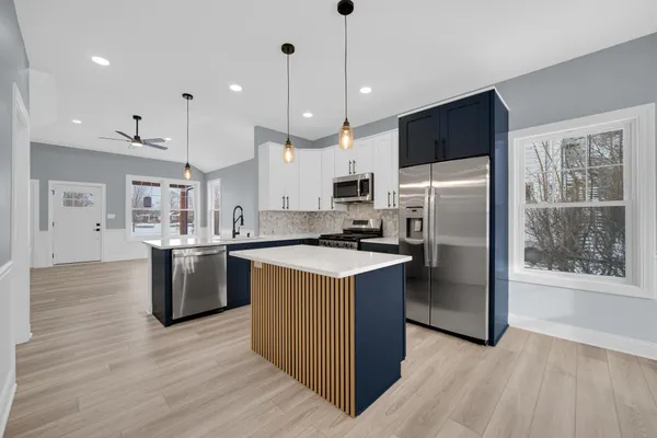 a kitchen with a refrigerator a microwave oven a sink with wooden floor and cabinets