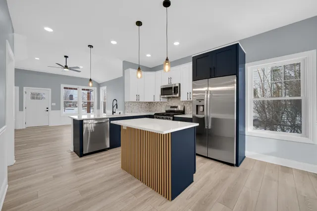 a kitchen with a refrigerator a microwave oven a sink with wooden floor and cabinets