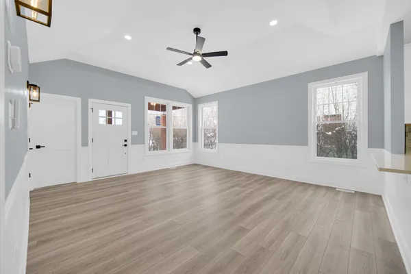 a view of an empty room with wooden floor and a window