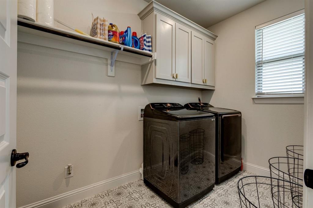 9613 Boulder Pt Road Oak Point, TX 75068 - Photo 27 of 28 Laundry area featuring patterned tile flooring, light-toned cabinetry with gold-toned hardware, a window with blinds, a wall-mounted shelf, and a clothing rod