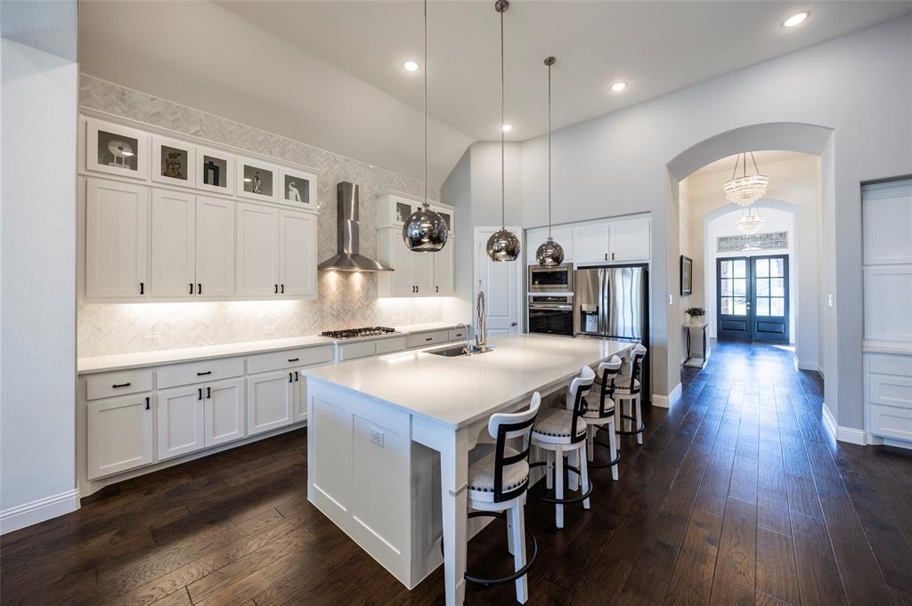 1650 Oakcrest Drive Prosper, TX 75078 - Photo 14 of 40 Kitchen featuring arched walkways, white cabinets, dark wood-type flooring, a breakfast bar, and high vaulted ceiling