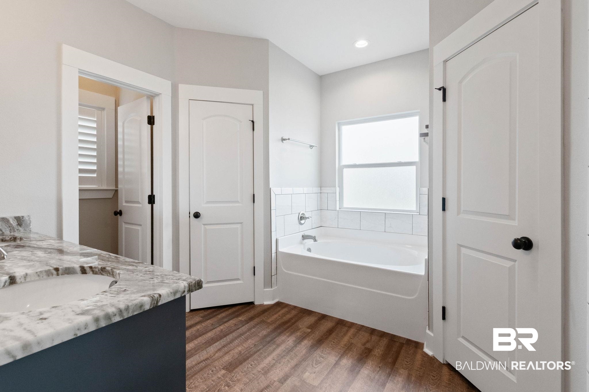 17376 Bankhead Boulevard Fairhope, AL 36532 - Photo 38 of 73 Bathroom with a garden tub, double vanity, dark wood-style flooring, and a closet